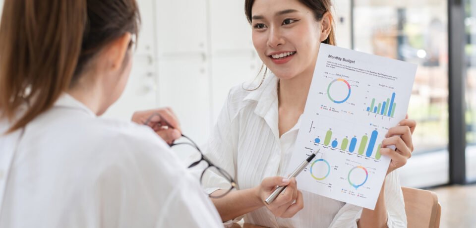 Young businesswoman and colleague working together, analyzing financial data and discussing strategies in a modern office.
