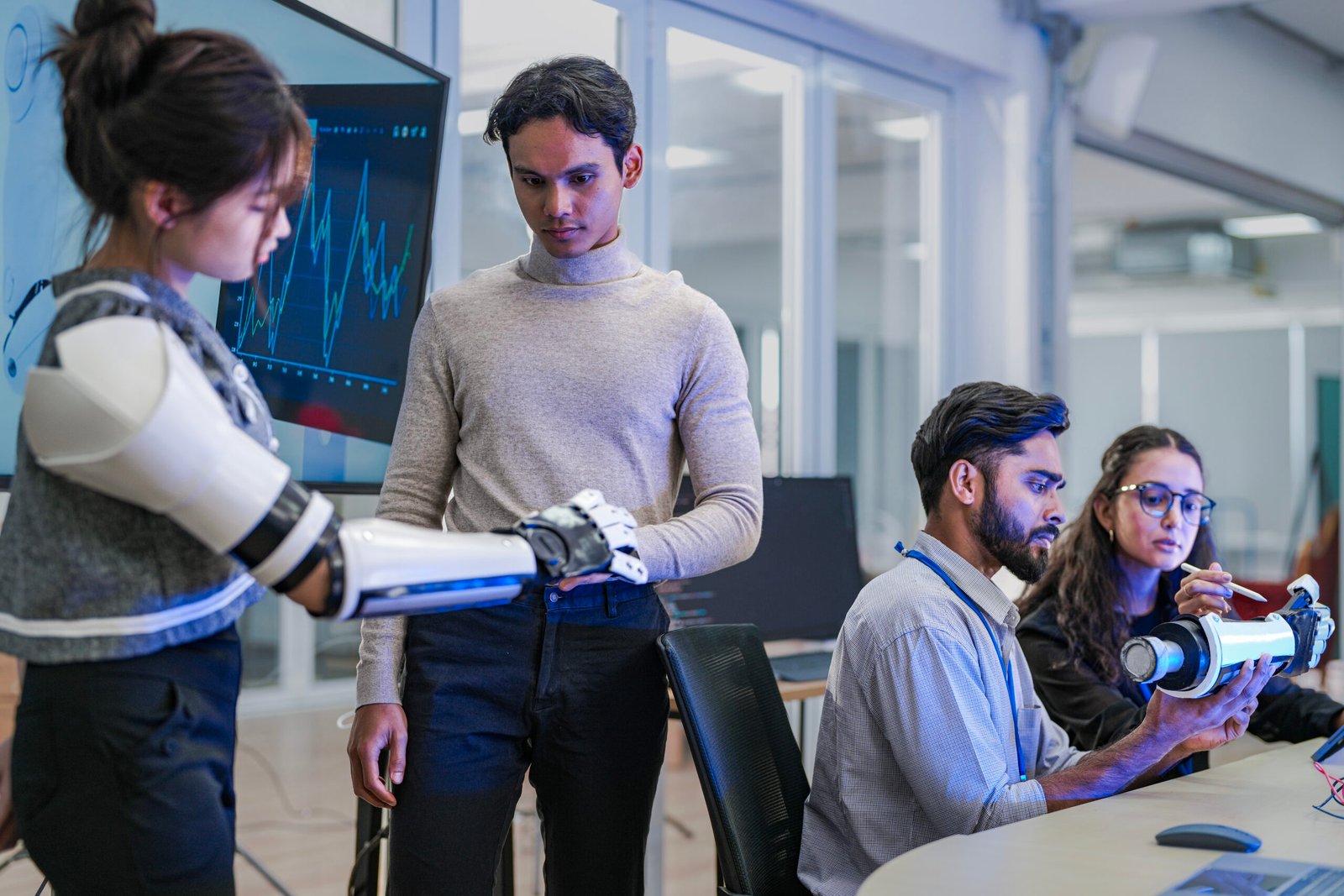 A robotics team develops a new bionic limb, inspecting the prototype while analyzing real-time performance data. A concept for digital twins, agile R&D, and mechatronics innovation.