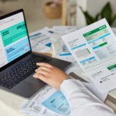 Cropped shot of unknown accountant and bookkeeper makes audit of expenses works with financial report at home uses laptop computer studies graphics uses online banking prepares business project