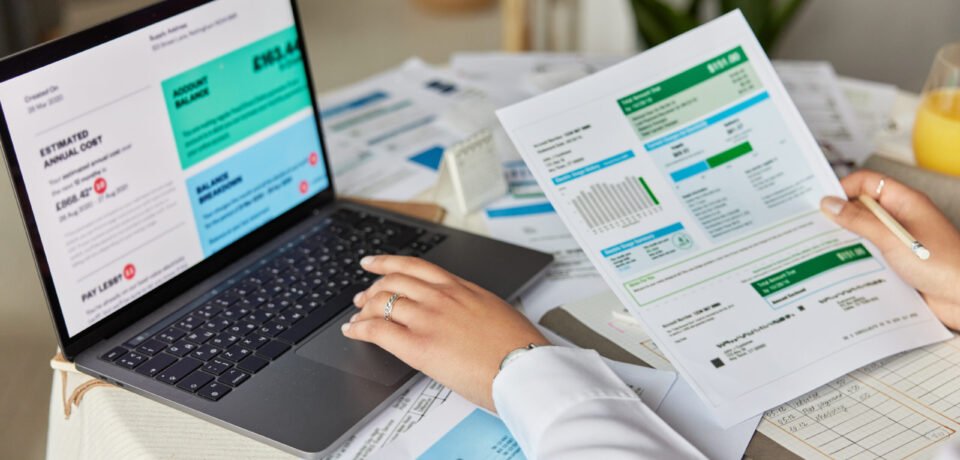 Cropped shot of unknown accountant and bookkeeper makes audit of expenses works with financial report at home uses laptop computer studies graphics uses online banking prepares business project