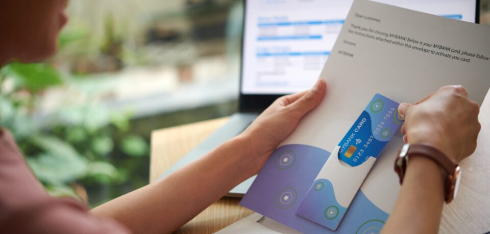 Hands of woman taking credit card out of letter from bank