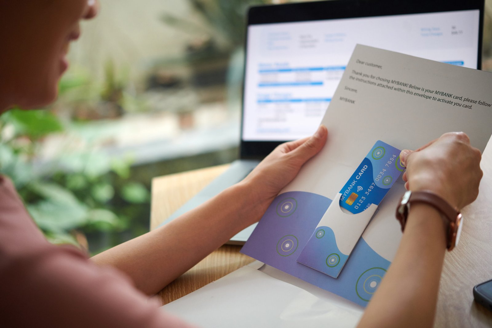 Hands of woman taking credit card out of letter from bank
