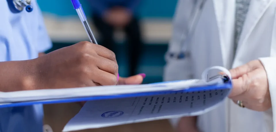 close-up-of-nurse-taking-notes-on-papers-wtih-help-2025-02-17-05-23-00-utc (1)