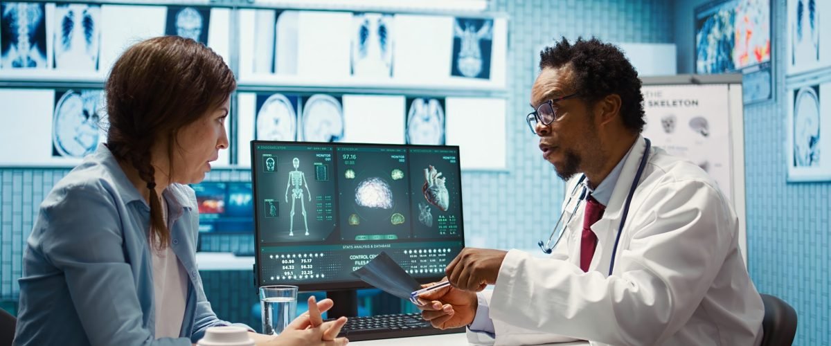 Medical expert specialist explaining the x ray imaging for a diagnosis, doing scan interpretation during check up consultation. Professional medic gives feedback to female client. Camera B.