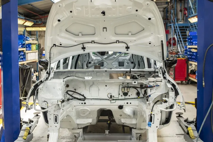 New white car with open hood at a factory