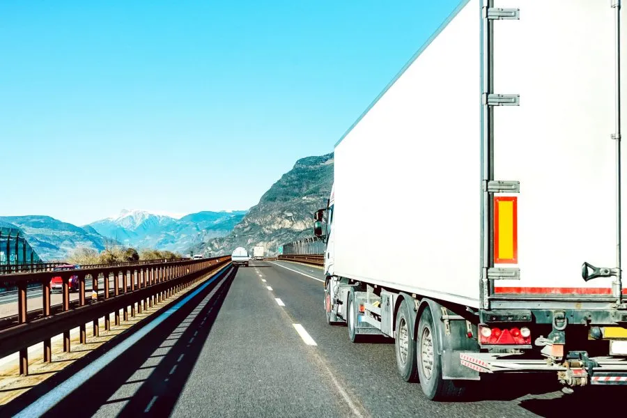 Semi truck speeding on empty highway line - Transport logistic concept with semitruck container driving on speedway - Focus on central part of background