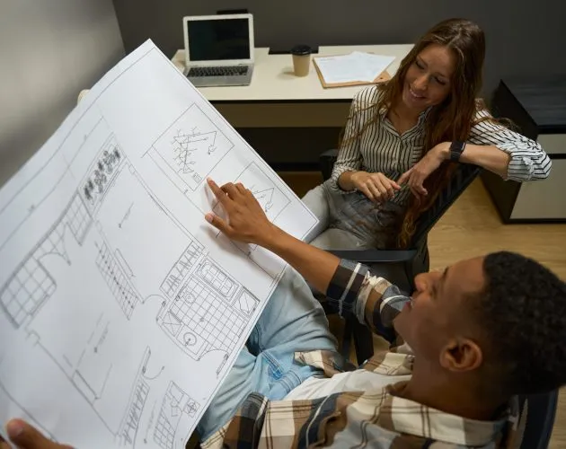 Two colleagues sitting and looking at drawing discussing a new project in the office